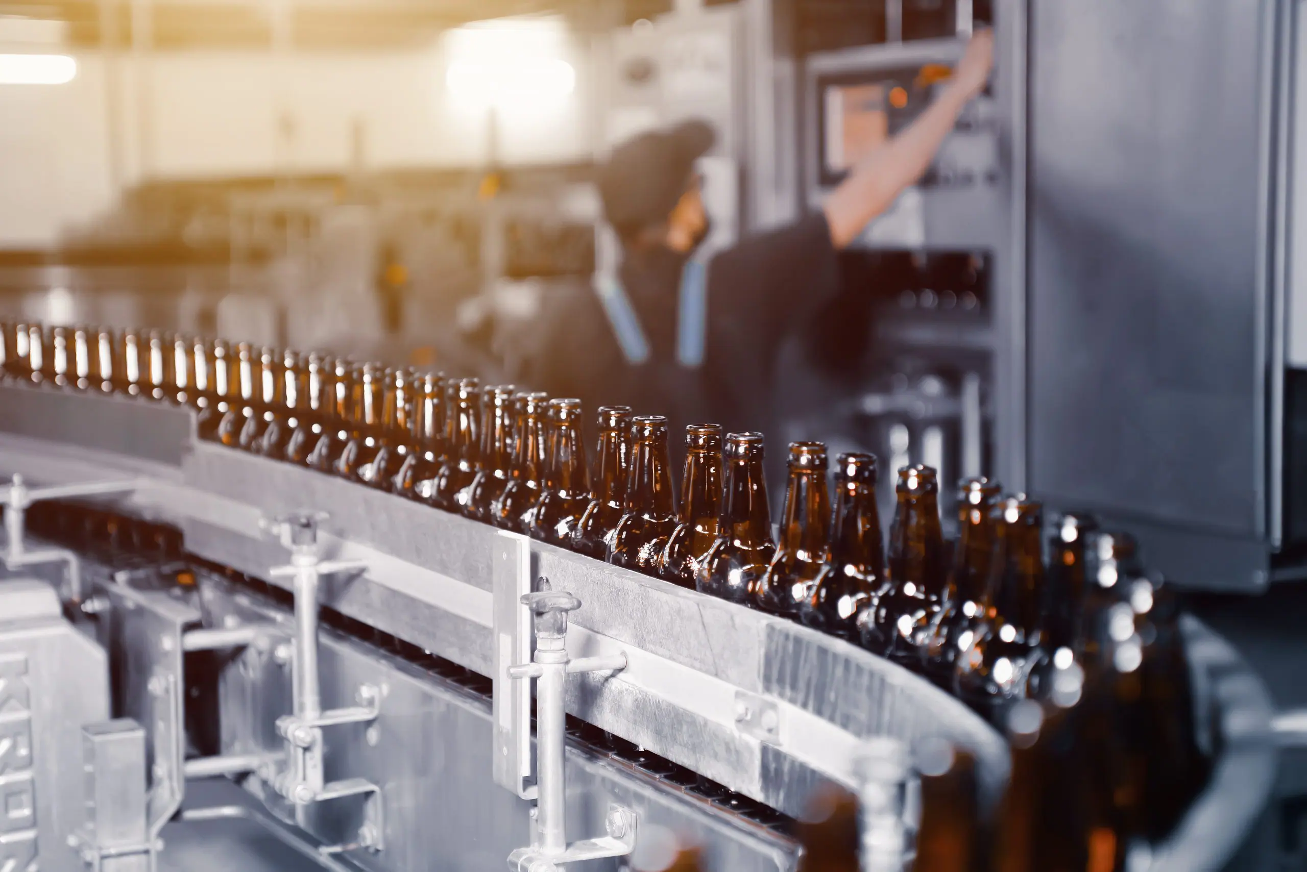 Garrafas de cerveja de vidro de cor marrom na linha transportadora de envasamento de cervejas close up