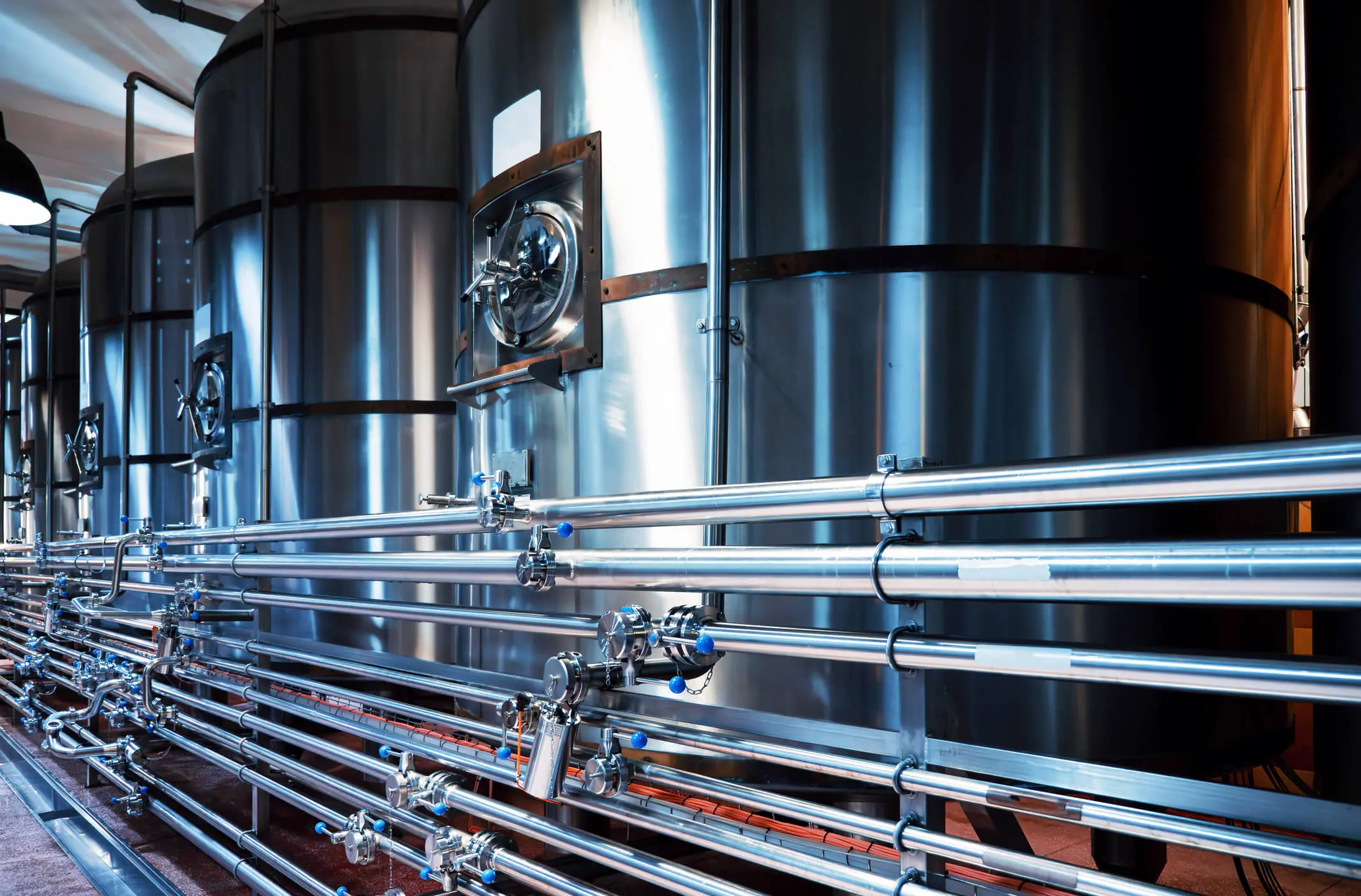 Tanques modernos de aço para cervejaria e tubagens complexas, precisão e qualidade na produção artesanal de cerveja.